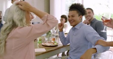 Çeşitli arkadaşlar, evdeki yemek masasına gül şarabı dökerken kadeh kaldırmayı kutluyorlar. Kutlama, neşe, sosyalleşme, arkadaşlık, zarafet, rahatlık, yaşam tarzı