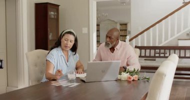 Üst düzey çift evde dizüstü bilgisayar ve çiçeklerle kutlama planlıyor, içten bir gülümsemeyle. yaşlılar, teknoloji, dijital aygıt, mutluluk, yaşam tarzı