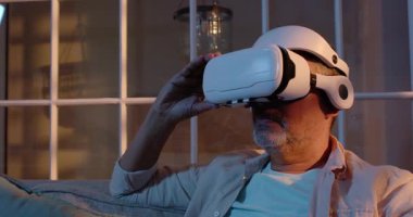 Evde sanal gerçeklik deneyimini keşfetmek için VR kulaklık kullanan kıdemli bir adam. teknoloji, fütürist, yenilik, dijital, daldırma