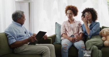 Aynı cinsiyetten lezbiyen çift evdeki oturma odasındaki kanepede terapistle sohbet ediyor. Danışmanlık, ilişki, iletişim, terapi, psikolog, destek