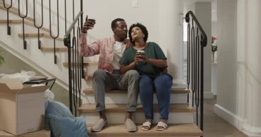 Merdivenlerde oturan, kahvelerini yudumlayan ve kutularını açan bir çift. birlikte, taşınma, taşınma, yaşam tarzı, yeni ev, geçiş