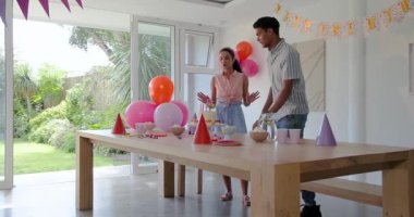 Çeşitli çiftler doğum günü partisinde renkli balonlarla etkileşime girerek neşeli havanın tadını çıkarıyorlar. Kutlama, neşe, evde, parti, mutluluk, eğlence, nişan, dekorasyon, gençlik