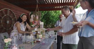 Bahçe partisinde, farklı yaşlılar bahçede gün ışığında sosyalleşip kutlama yapıyorlar. Kutlama, dostluk, olgun, toplanma, boş zaman, mutluluk