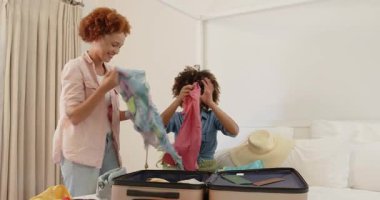 Çift cinsiyetli lezbiyen çift evde bavullarını topluyor, tatil gezisine hazırlanıyorlar. LGBTQ, seyahat, tatil, ilişki