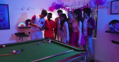 Çeşitli arkadaşlar doğum günü için bilardo masasında akıllı telefon büyütüp disko topunun altında dans ediyorlar. Kutlama, dostluk, gece hayatı, coşku, eğlence, sosyalleşme, parti