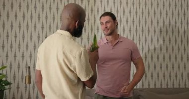 Çeşitli erkek arkadaşlar evde sarılıyorlar, yeşil bira şişelerini kapıyorlar kanepede sohbet ediyorlar. Arkadaşlık, dostluk, kutlama, rahatlık, rahatlama, sosyalleşme, yaşam tarzı.