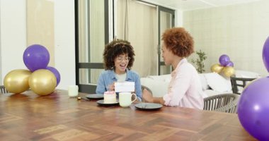 Doğum günü kutlaması, neşeli lezbiyen çift evde pasta ve balonlarla hediyelerini değiş tokuş ediyorlar. Kutlama, mutluluk, parti, yıldönümü, romantizm, sürpriz