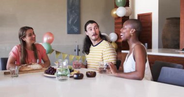 Arkadaşlar evde toplanıp, yemek yiyip, kahkahalar atıyorlar. Arkadaşlık, kutlama, yemek, ziyafet, sosyalleşme, mutluluk.