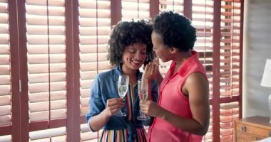 Nişanı şampanyayla kutlayan, gülümseyen ve evde neşeyi paylaşan iki kadın. Kutlama, mutluluk, arkadaşlık, bağ, şerefe