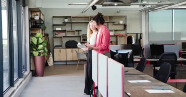 Çeşitli iş arkadaşları modern iş yerinde tabletleri tavandan tavana kadar tutarak birbirlerine sarılıyorlar. Meslektaşlar, takım çalışması, destek, güven, arkadaşlık, üretkenlik, çalışma alanı