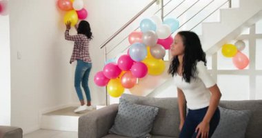 Çeşitli bayan arkadaşlar, ellerinde cips ve sos tepsisi olan parlak mutfaktaki duvarlara balon yapıştırıyorlar. Parti, şenlik, dekorasyon, aperatif, konut, modern, günlük