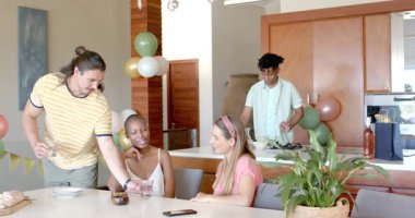 Partide, evde kutlama yaparken, arkadaşlar içki içerken ve dekorasyonlarla neşeli sohbetler ederken. Parti, kutlama, arkadaşlık, sosyalleşme, toplanma, mutluluk