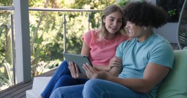 Video sohbeti, balkonda dinlenen genç bir çift birlikte tablet izlerken kahkahalarını paylaşıyorlar. Rahatlama, bağlanma, rahatlama, teknoloji, dijital cihaz, yaşam tarzı