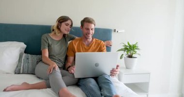 Video sohbeti, çift dizüstü bilgisayarla yatakta dinleniyor, evde güzel vakit geçiriyor. Yaşam tarzı, eğlence, teknoloji, rahatlama, birliktelik, bağ.