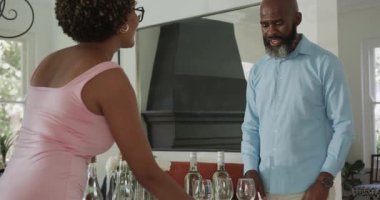 Çeşitli arkadaşlar ev masasında şarap kadehlerini sıraya dizip içki masasını hazırlıyorlar. Sosyalleşme, kutlama, zarafet, rahatlık, entelektüellik, arkadaşlık, misafirperverlik.