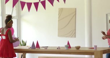 Afro-Amerikalı çift çocukların doğum günü evlerine ev sahipliği yapıyor, renkli afişler ve malzemeler asıyorlar. Kutlama, dekorasyon, coşku, aile, parti, neşe, hazırlık