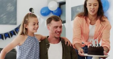 Çeşitli aileler, annemin eve doğum günü pastası getirmesini, babamın mum üflemesini, kız kucaklamasını izliyor. Aile, kutlama, neşe, birliktelik, sıcaklık, şefkat, mutluluk.