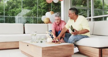 Modern ev ortamında ahşap masa ve tatlılarla 60. doğum gününü kutlayan kıdemli arkadaşlar. Kutlama, dostluk, toplanma, neşe, hoşgörü, evde, modern