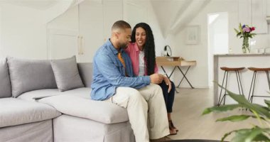 Oturma odasına girip koltukta oturan çift alışveriş fikirleri için akıllı telefon içeriğini araştırıyor. Romantik, samimiyet, bağlantı, eğlence, modern, samimi, yaşam tarzı