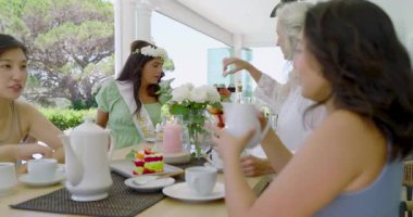 Çeşitli bayan arkadaşlar çay dolduruyor, son sınıftan sonra kucaklaşıyorlar, verandada kek sohbetlerine devam ediyorlar. Dost canlısı, sosyal, boş, köylü, samimi, içten, uyumlu.