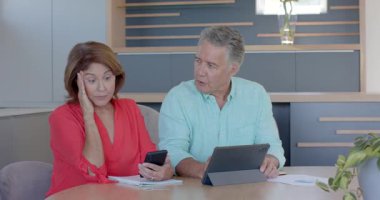 Olgun bir erkek ve yaşlı bir kadın tıkırtı tabletini okşarken, kaş çözme sorunuyla karşı karşıya. İşbirliği, takım çalışması, iletişim, teknoloji, yaş farklılığı, problem çözme, modern