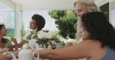 Sunbae, gelin jestini fark ediyor, çay dolduruyor ve terasta kutlama kekleri servis ediyor. Kutlama, dostluk, zarafet, açık hava, neşe, sıcaklık, samimiyet.