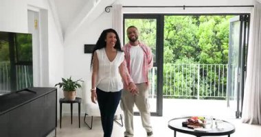 Bir çift oturma odasına giriyor, kadın kırmızı gül sunuyor, adam diz çökmüş nişan yüzüğünü gösteriyor. Romantizm, kutlama, bağlılık, sevgi, ev, neşe, mahremiyet