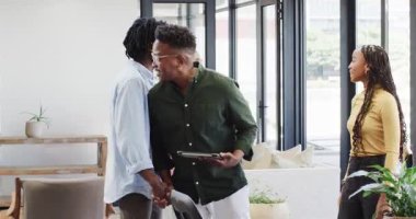 Afro-Amerikan takımı el sıkışıyor tableti tıkırdatıyor, veri güncellemelerini gösteriyor, ofis salonunda toplanıyorlar. İşbirliği, takım çalışması, modern, profesyonel, iletişim, yenilik, gelişigüzel