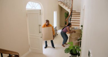 Afrika kökenli Amerikalı bir adam merdivenin yanındaki yeni evdeki kutuları açıyor, odaklanmış görünüyor. Taşınma, taşınma, ev sahipliği, yaşam tarzı, kapalı alan, konsantrasyon