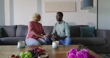 Kanepede oturan, gülümseyen ve evdeki sohbetin tadını çıkaran bir çift. yerel, ilişki, oturma odası, mutluluk, bağ, birliktelik