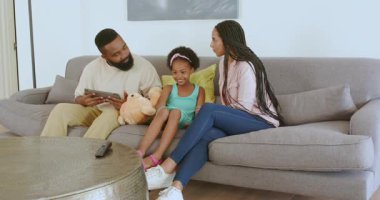 Çeşitli aileler oturma odasında yeni kardeş haberlerini tablet ve oyuncak ayıyla kutluyor. Aile, duyuru, sevinç, bağlanma, konforlu, modern, mutluluk, birliktelik