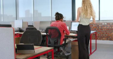 Modern ofiste çalışan çeşitli iş arkadaşları, teknolojik aletlerle belgeleri gözden geçiriyorlar. İşbirliği, çalışma alanı, teknoloji, tartışma, üretkenlik, kentsel, profesyonellik