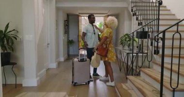 Çeşitli arkadaşlar, modern ev girişinde bavullarıyla sevinçle kucaklaşıyorlar. Dostluk, birleşme, selamlama, bavul, misafirperverlik, seyahat