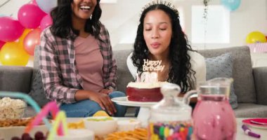 Oturma odasındaki kanepede oturan çeşitli bayan arkadaşlar, kırmızı kadife kek ve balonların tadını çıkarıyorlar. Doğum günü partisi, kutlama, şenlik, toplanma, ev, canlı, renkli.