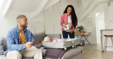 Çeşit çeşit çift tablet danışmanlık ve yaklaşan gezi için tavan arası oturma odasında bavul paketleme. Seyahat, paketleme, yaşam tarzı, modern, işbirliği, macera, organizasyon