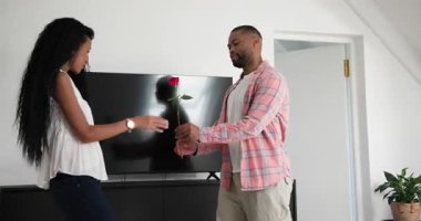 Oturma odasına giren, değişik çiftler etrafı keşfederken diz çöküp gül ve nişan yüzüğü sunan bir adam. Romantizm, öneri, sevgi, kutlama, samimiyet, neşe, modern