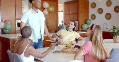 Arkadaşlar mutfak masasının etrafında sohbet ve atıştırmalıklardan hoşlanıyorlar. Kutlama, arkadaşlık, sosyalleşme, toplanma, aşçılık, eğlence