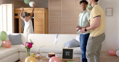 Arkadaşlar evde kutlama yapıyor, balonlar ve dekorasyonlarla dans ediyor ve gülüyorlar. Parti, kutlama, eğlence, mutluluk