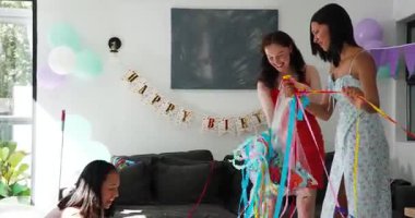 Çeşitli bayan arkadaşlar doğum günü temizliği sırasında oturma odasındaki plastik torbaya flama sokuyorlar. Kutlama, dostluk, takım çalışması, dekor, iç mekan, neşe, renkli