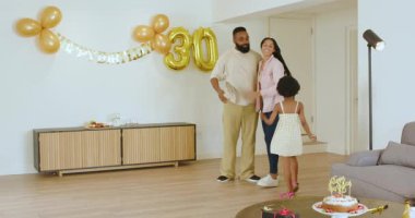 Çeşitli aileler modern oturma odasında doğum günü pastası ve parti şapkalarıyla doğum günlerini kutluyorlar. Kutlama, aile, neşe, birliktelik, modern, şenlikli, atmosfer, parti