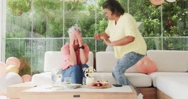 60. doğum gününü dışarıda şık bir kanepede kutlayan son sınıf arkadaşları pasta ve şenlik dekorunun tadını çıkarıyorlar. Kutlama, dostluk, neşe, açık hava, coşku, emeklilik, dekor, toplanma, pasta