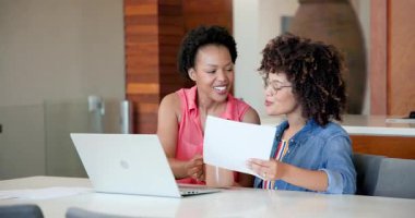 Evde dizüstü bilgisayarla iş birliği yapan iki kadın, odaklanmış ve tartışma içindeler. İşbirliği, takım çalışması, beyin fırtınası, uzaktan çalışma, teknoloji, iletişim