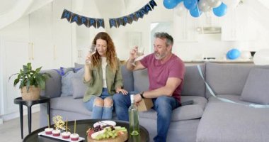 Çift doğum gününü sehpanın yanındaki koltukta kutluyor, hediye saatini açıyor, keklerini paylaşıyor. Romantizm, kutlama, yakınlık, zarafet, neşe, neşe, hayat tarzı.