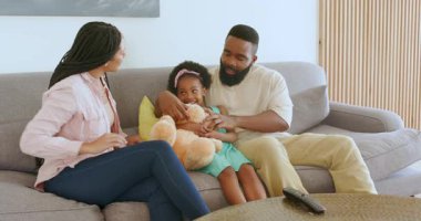 Çeşitli aile, uzaktan kumandalı rahat oturma odasındaki kanepede kardeş sürprizi yapıyor. Aile, duyuru, heyecan, birliktelik, rahatlık, konfor, yaşam tarzı, neşe, ebeveynlik