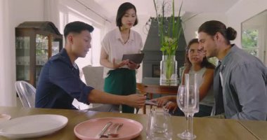 Asyalı tasarım ekibi kumaş örnekleri hazırlıyor ve yemek masasında müşterilere rehberlik ediyor. Renkleri belirliyorlar. İşbirliği, yaratıcılık, modern, estetik, danışma, ev, görselleştirme