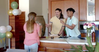 Partide, Arkadaşlar modern mutfakta içkilerle kadeh kaldırıyor, neşeyle kutluyorlar. Kutlama, arkadaşlık, parti, toplanma, mutluluk, keyif