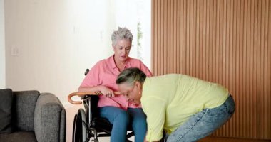 Üst düzey arkadaşlar modern oturma odasında iyileşme sürecini baston ve tekerlekli sandalyeyle kutluyorlar. Kutlama, dostluk, destek, iyileşme, refah, konfor, içişleri, arkadaşlık, olumlu