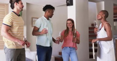 Arkadaşlar evde toplanıyor, ellerinde şampanya bardakları, gülümsüyor ve sohbet ediyorlar. Kutlama, arkadaşlık, parti, kadeh kaldırma, tezahürat, yaşam tarzı