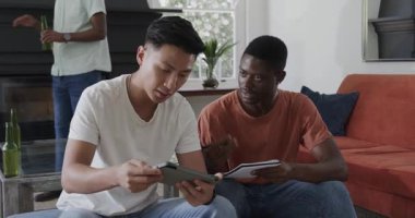 Farklı erkek arkadaşlar tablet kullanıyor. Yetişkinlerin oturma odasına bira şişesiyle girmelerine tepki veriyorlar. İşbirliği, sosyalleşme, eğlence, modern, iç mekan, iletişim, yoldaşlık