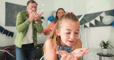 Çeşitli aileler evde kutlama partisi veriyor. Küçük kız konfeti üflüyor ve ebeveynler flama fırlatıyor. Aile, kutlama, neşe, birliktelik, şenlikli, renkli, ebeveynlik